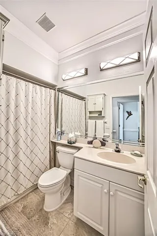 Bathroom with tile floors, ornamental molding, vanity, and toilet