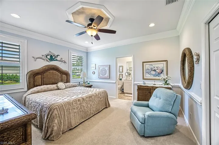 Bedroom featuring light colored carpet, ornamental molding, ceiling fan, and ensuite bath