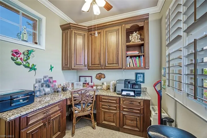 Tiled office with ceiling fan, ornamental molding, and built in desk