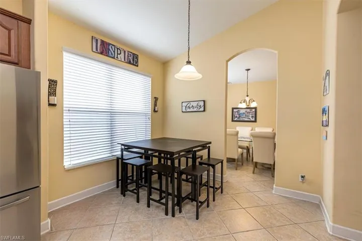 Dining space featuring arched walkways, light tile patterned floors, and lofted ceiling