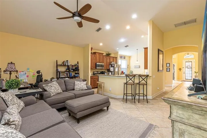 Living area with arched walkways, vaulted ceiling, ceiling fan, light tile patterned floors, and recessed lighting