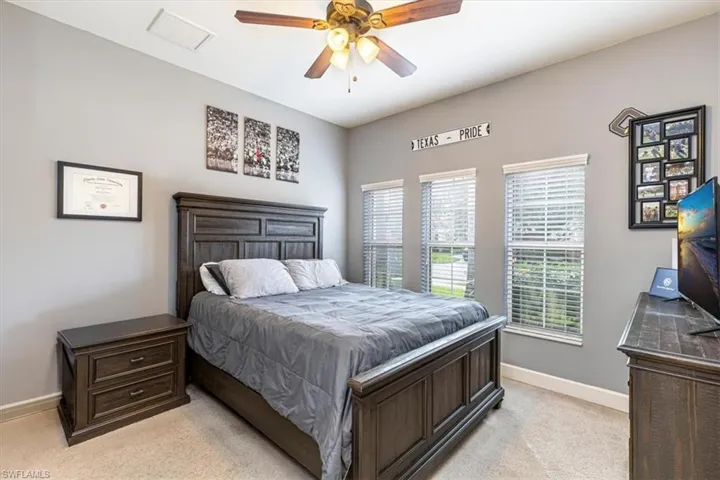 Bedroom with light colored carpet and a ceiling fan