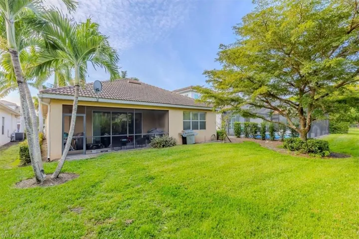 Back of property with a yard, a sunroom, stucco siding, and a tile roof