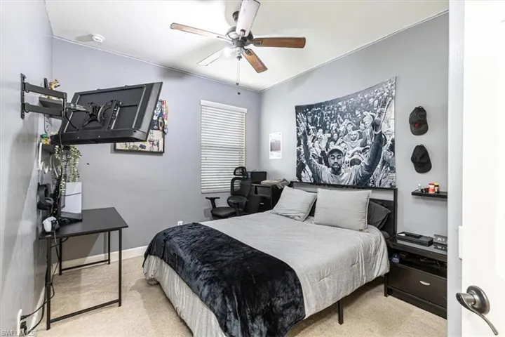 Bedroom with ceiling fan, a desk, and light colored carpet