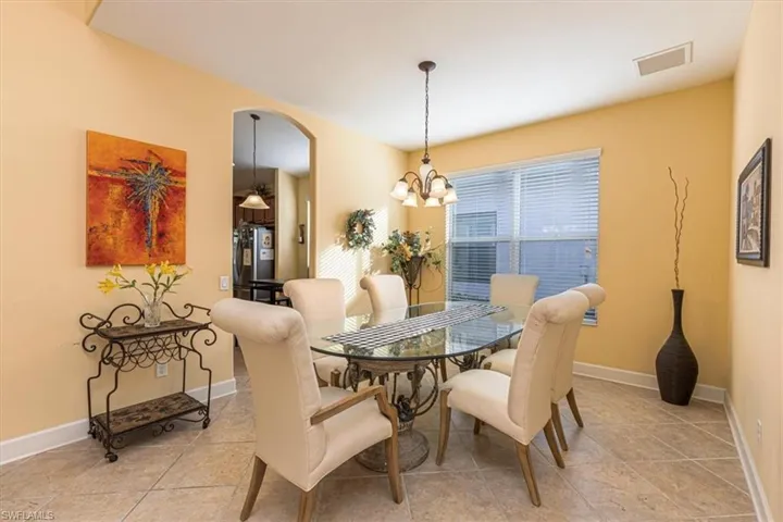 Dining area featuring arched walkways, a chandelier, and light tile patterned flooring