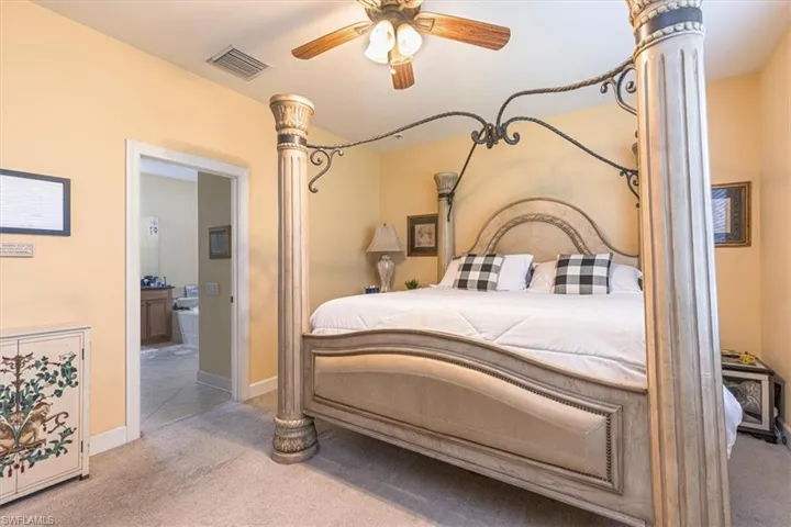 Bedroom with carpet, ceiling fan, ensuite bathroom, and ornate columns