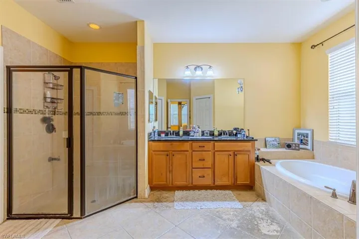 Full bath featuring a garden tub, a shower stall, double vanity, and light tile patterned floors