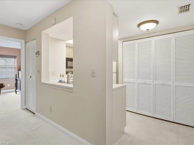 Pass-through window to kitchen, white louvered bifold doors, recessed lighting, and neutral wall tones