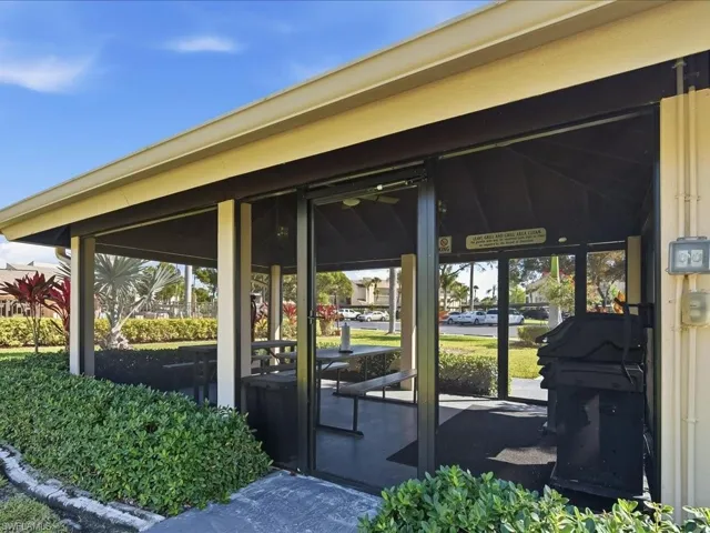 Screened outdoor pavilion with a built-in ceiling fan, concrete flooring, and an integrated picnic table