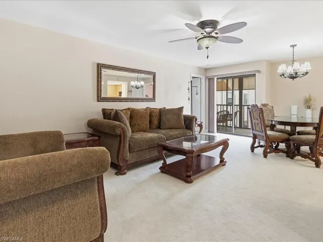 Living area featuring light-colored carpeting and a sliding glass door leading to an outdoor space