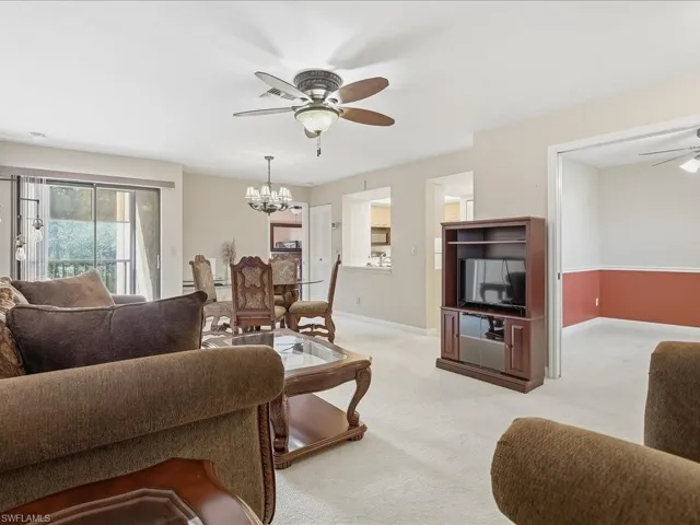 Open-concept living space with light-colored carpeting, ceiling fan, and sliding glass doors