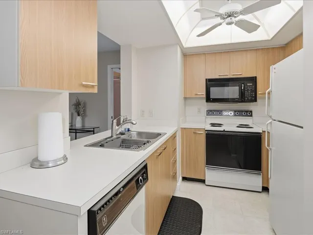 Kitchen featuring wood-finish cabinetry, white countertops, a double basin stainless steel sink, and built-in appliances