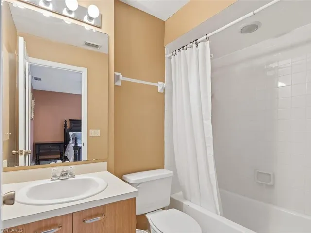 Bathroom featuring a single vanity with wood-finish cabinetry, an integrated sink, and a full-width mirror