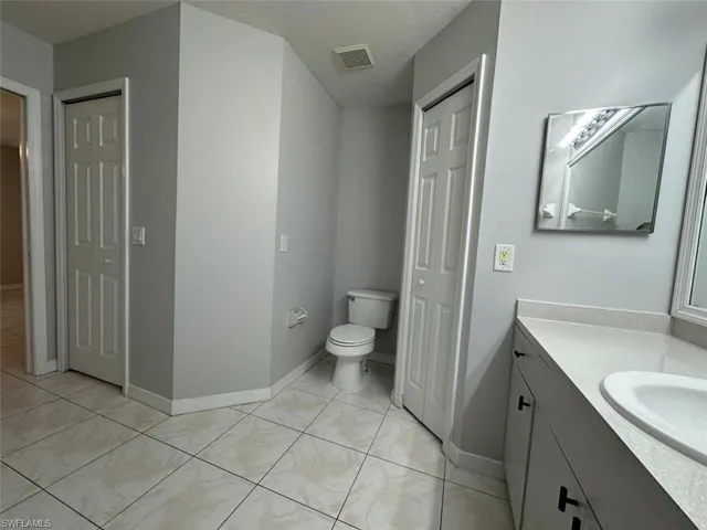 Bathroom featuring a closet, vanity, and light tile patterned floors