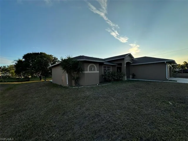Ranch-style house with stucco siding, a front yard, and a garage