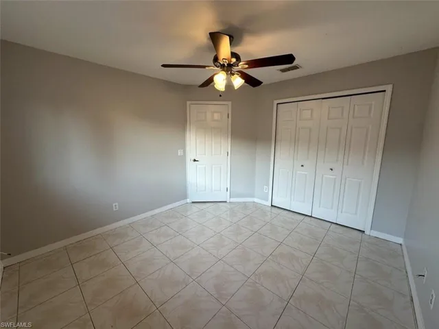 Unfurnished bedroom with a ceiling fan, a closet, and light tile patterned floors