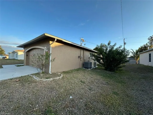 View of property exterior featuring stucco siding, driveway, a yard, and an attached garage