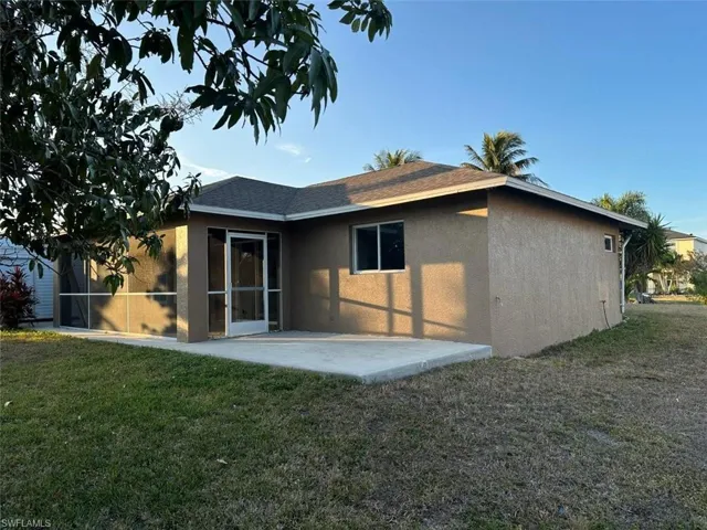 Back of house with stucco siding, a patio, a yard, roof with shingles, and a sunroom