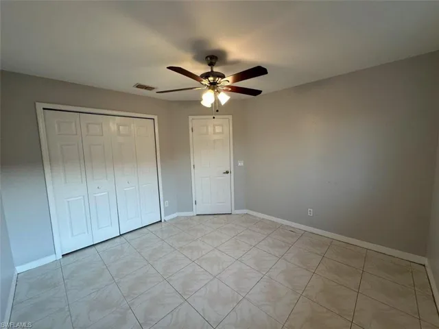 Unfurnished bedroom featuring a ceiling fan, a closet, and light tile patterned flooring