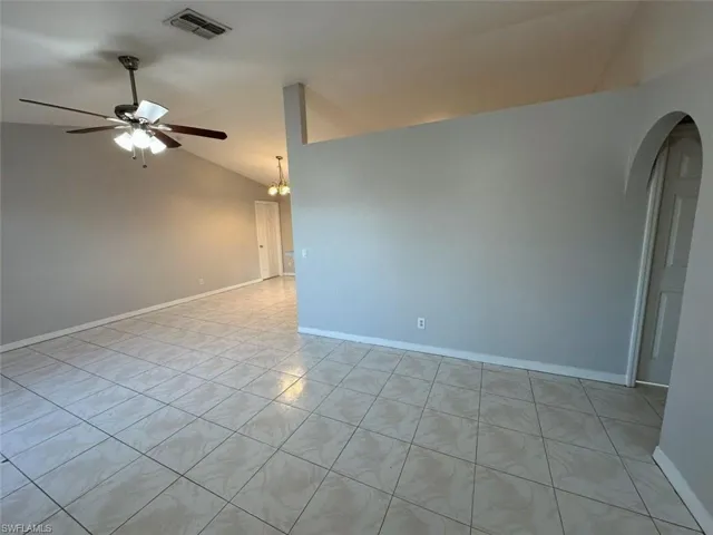 Unfurnished room featuring lofted ceiling, a chandelier, a ceiling fan, light tile patterned flooring, and arched walkways