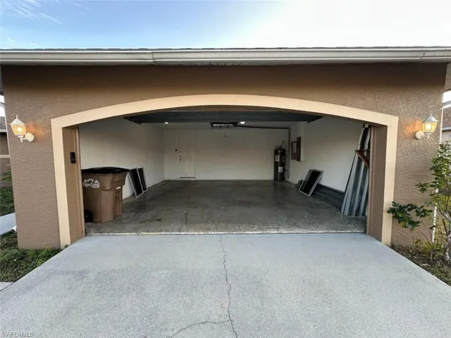 Garage featuring driveway, water heater, and electric panel