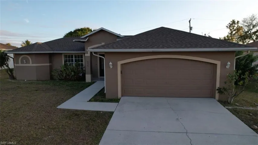 Single story home featuring stucco siding, roof with shingles, concrete driveway, a front yard, and a garage