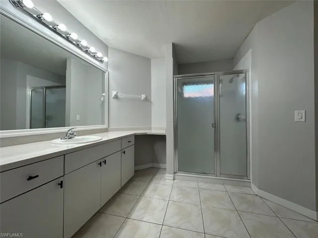 Bathroom with vanity, a shower stall, and a textured ceiling