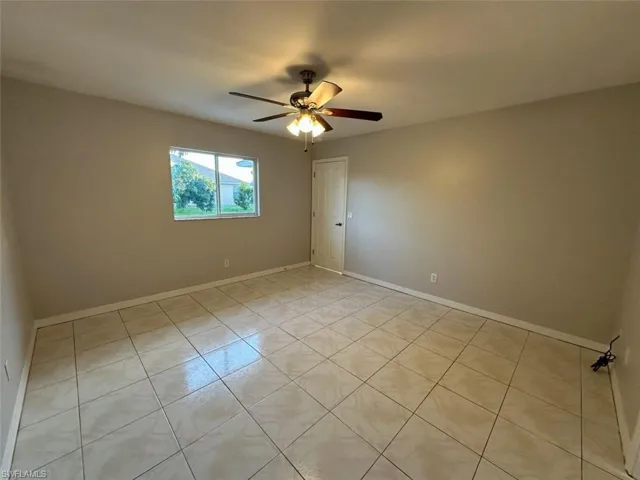 Empty room featuring a ceiling fan and light tile patterned floors