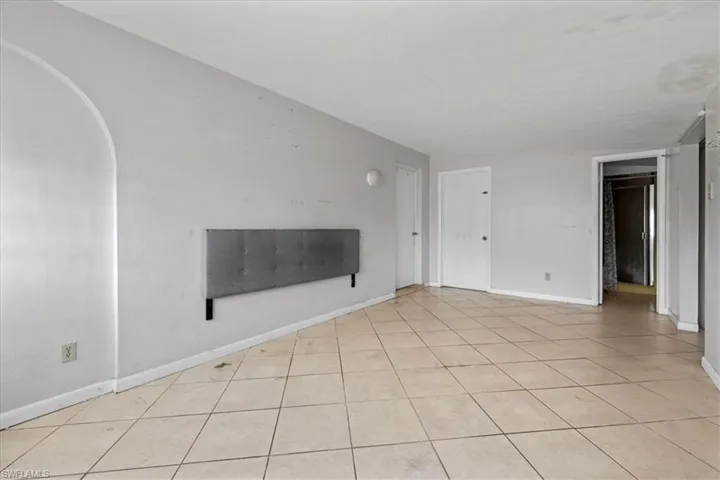Unfurnished living room with light tile patterned flooring and arched walkways