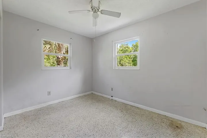 Empty room featuring speckled floor and a ceiling fan