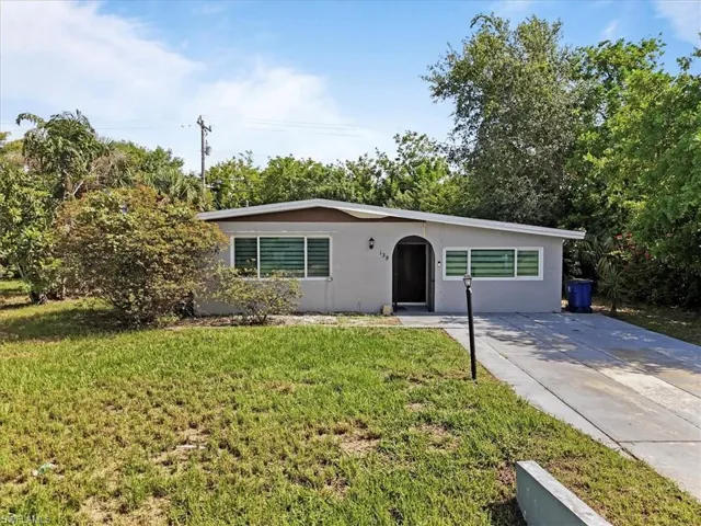 Ranch-style house with a front lawn, stucco siding, and driveway