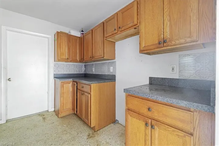 Kitchen with brown cabinetry, dark countertops, and decorative backsplash