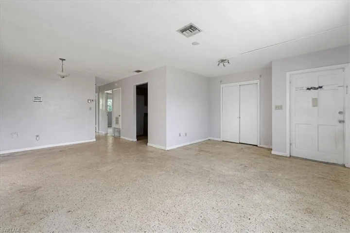 Unfurnished living room with speckle patterned floor and baseboards