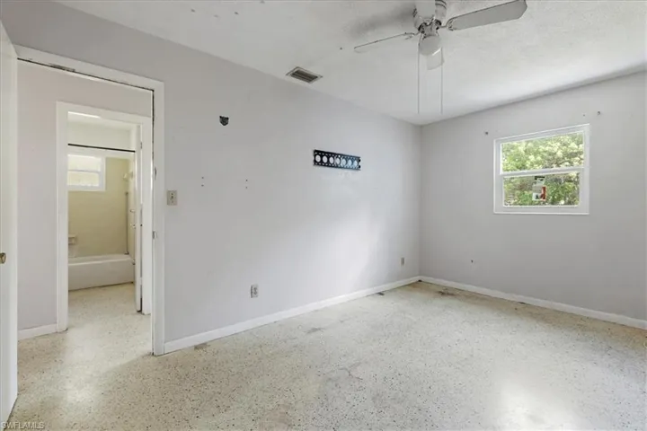 Unfurnished room with speckled floor, plenty of natural light, and a ceiling fan