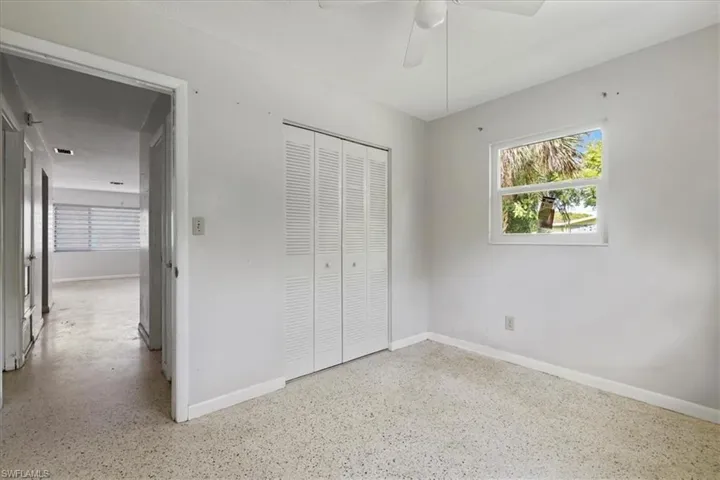 Unfurnished bedroom with speckled floor, a closet, and a ceiling fan