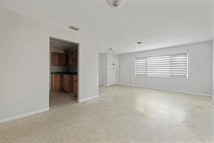 Unfurnished living room with baseboards and dark aggregate flooring