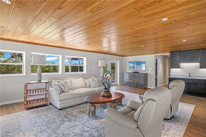 Living room with ornamental molding, sink, light hardwood / wood-style flooring, and wood ceiling