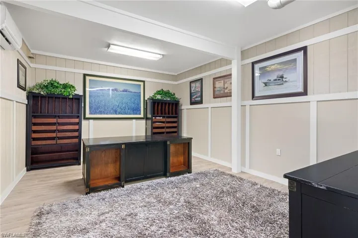 Unfurnished office featuring light hardwood / wood-style floors, a wall unit AC, and ornamental molding