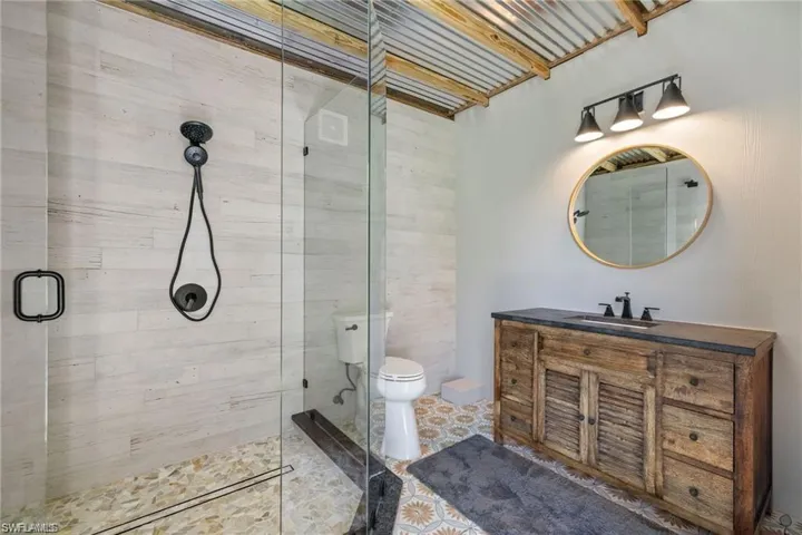 Bathroom featuring toilet, tile patterned flooring, vanity, and a shower with door