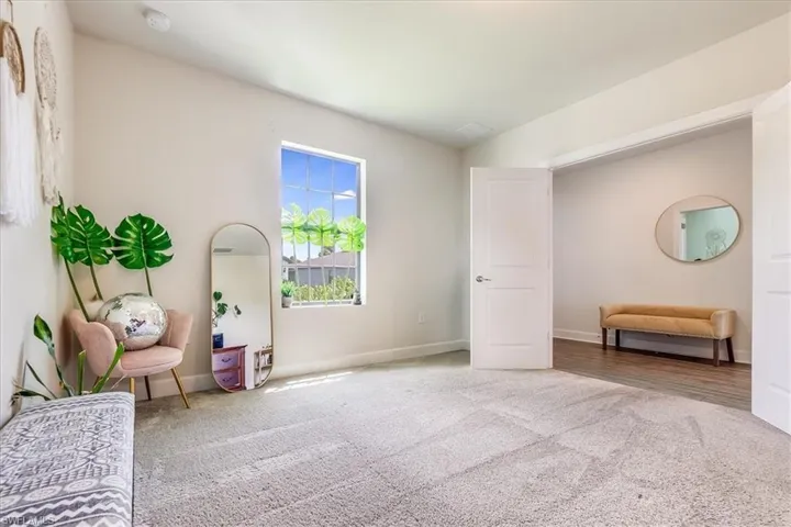Den with double doors featuring light colored carpet
