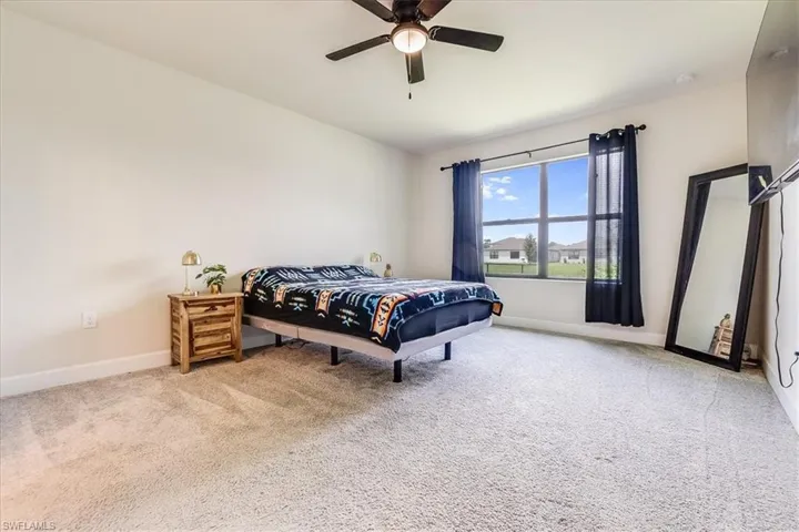 Bedroom with ceiling fan and light carpet