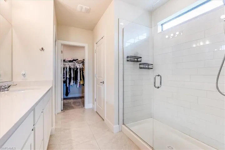 Bathroom with tile patterned flooring, an enclosed shower, and double vanity