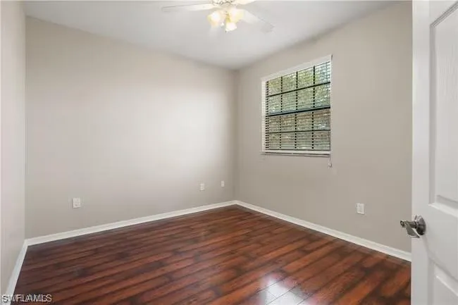 Unfurnished room featuring dark wood-type flooring and a ceiling fan