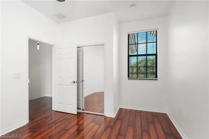 Unfurnished bedroom featuring a closet and dark wood-style flooring