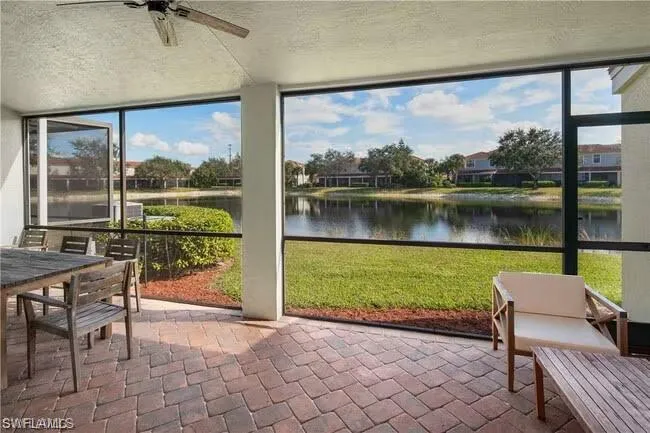 Sunroom with a water view, ceiling fan, expansive windows, outdoor dining space, and a patio