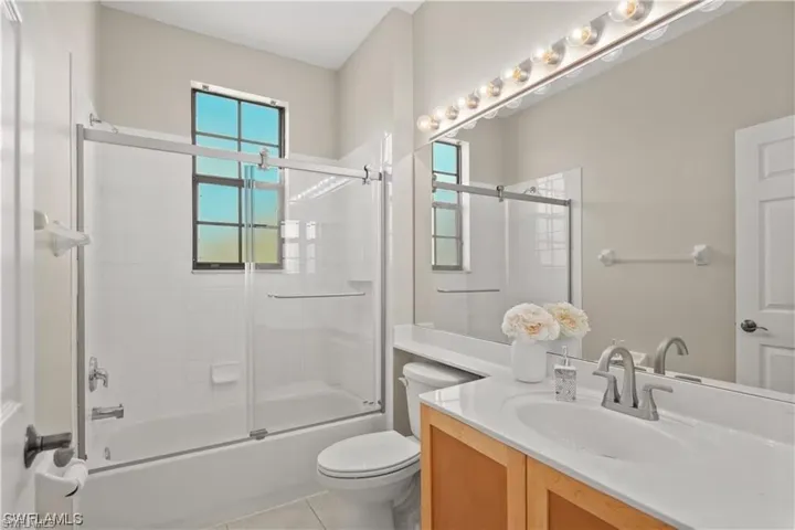 Bathroom featuring vanity, combined bath / shower with glass door, and light tile patterned flooring