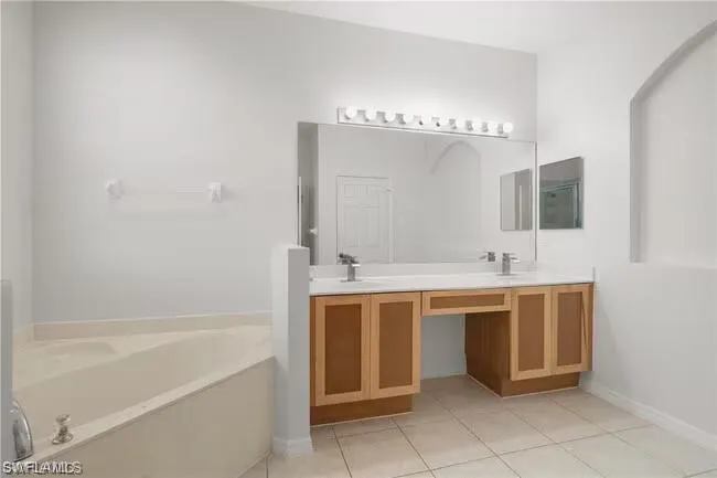 Full bathroom with a bath, double vanity, and light tile patterned floors