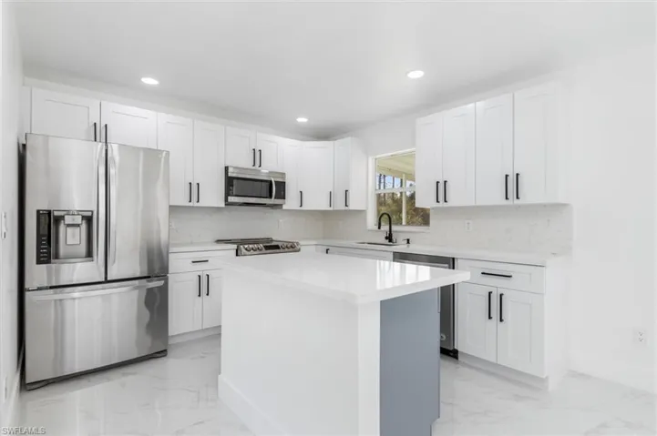 Kitchen featuring white cabinetry, stainless steel appliances, sink, and a kitchen island