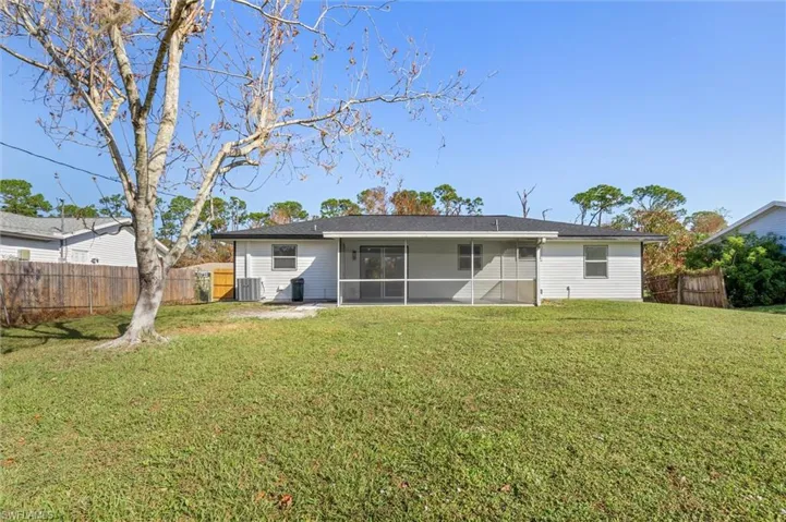 Rear view of property with a sunroom and a lawn