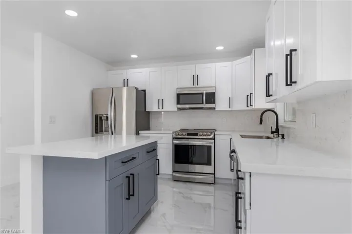 Kitchen with a kitchen island, white cabinetry, sink, gray cabinetry, and stainless steel appliances